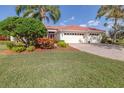 Inviting home with a brick driveway, lush green lawn, tropical landscaping, and a clay tile roof at 6209 Cypress Bend Ct, Bradenton, FL 34201