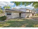 A townhouse showcasing its neutral exterior and a small lawn area, complemented by nearby trees and a glimpse of a park at 8001 Jasmine Dr # 8001, Temple Terrace, FL 33637