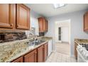 Well-lit kitchen boasts granite countertops, stainless steel sink, dishwasher, and stylish tiled backsplash at 10038 62Nd N Ter # 1, St Petersburg, FL 33708