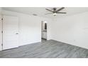 Open bedroom with wood-look flooring, a modern ceiling fan, and an en-suite bathroom view at 114 25Th E St, Palmetto, FL 34221