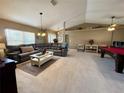 Expansive living room showcasing a plush sectional sofa, pool table, and neutral tile flooring at 22941 Leafwood Ct, Land O Lakes, FL 34639