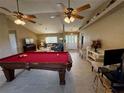 Open-concept living area featuring a pool table, tile flooring, and multiple ceiling fans for comfort at 22941 Leafwood Ct, Land O Lakes, FL 34639