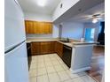 Efficient kitchen with wood cabinetry, black appliances, and breakfast bar overlooking living area at 5125 Palm Springs Blvd # 1203, Tampa, FL 33647