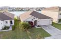 Aerial view of home, highlighting the well maintained yard, lake view, and two car garage at 7771 Davie Ray Dr, Zephyrhills, FL 33540