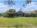 Charming stone home with covered patio, a well-manicured lawn, and a peaceful, inviting atmosphere at 7843 Shoupe Rd, Plant City, FL 33565