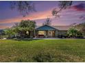 Beautiful stone home with covered porch and manicured lawn at sunset, creating a warm ambiance at 7843 Shoupe Rd, Plant City, FL 33565