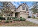 Two-story beige house with well maintained yard and mature landscaping at 10909 Observatory Way, Tampa, FL 33647
