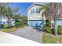 Two-story townhome with neutral siding, a blue garage door and brick paver driveway at 1109 Lady Gouldian Ct, Tampa, FL 33613