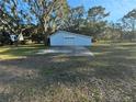 A detached one car garage features white siding, concrete apron and decorative trim at 12272 Eakin St, Weeki Wachee, FL 34614