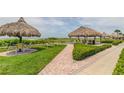 Well manicured lawn and brick path leading to the sandy beach with tiki umbrellas and chairs at 1460 Gulf Blvd # 506, Clearwater Beach, FL 33767