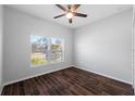 Bright bedroom with a large window, ceiling fan, and sleek wood-look tile flooring at 1593 Secluded Garden Ln, Lutz, FL 33558