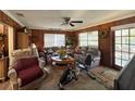 Cozy living room featuring wood-paneled walls, comfortable seating, and a ceiling fan for a relaxed atmosphere at 18401 Hamilton Rd, Dade City, FL 33523