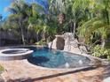 Beautiful pool area featuring a rock waterfall, lush landscaping, and relaxing spa at 681 Jasmine S Way, St Petersburg, FL 33705