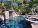 Beautiful pool area featuring a rock waterfall, lush landscaping, and relaxing spa at 681 Jasmine S Way, St Petersburg, FL 33705