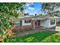 Single story home featuring brick accents, a cozy front porch sitting area, and a well-maintained front lawn at 3112 S Julia Cir, Tampa, FL 33629