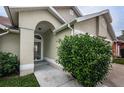 Covered entryway featuring a arched front doorway framed by lush landscaping at 319 Wood Ibis Ave, Tarpon Springs, FL 34689