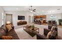Open-concept living room with a ceiling fan, leading into a kitchen with wooden cabinets and a dining area at 35478 Bellington Blvd, Zephyrhills, FL 33541