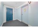 Condo hallway featuring neutral walls, carpeting and white trim with a blue residential door at 5220 Brittany S Dr # 1409, St Petersburg, FL 33715