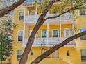 Bright yellow townhome with balconies on two levels, framed by trees at 958 Sombra St, Tampa, FL 33619