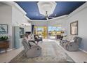 Bright living room with tile flooring, comfortable seating, blue accent ceiling, and sliding glass doors to the lanai at 12 Medalist Ter, Rotonda West, FL 33947