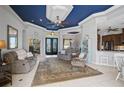 Open-concept living room with tile floor, leading to a breakfast bar and kitchen, featuring a stylish blue ceiling at 12 Medalist Ter, Rotonda West, FL 33947