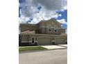 Charming exterior featuring a beige facade, tile roof, and a two-car garage at 1214 Godavari Way, Wesley Chapel, FL 33543