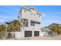 A charming three-story home featuring a two-car garage and balcony, set against a beautiful blue sky at 30 80Th Ter, Treasure Island, FL 33706