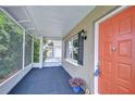 Cozy screened-in porch with painted concrete and space for seating, leading to a vibrant front door at 4772 Silver Cir, Zephyrhills, FL 33541