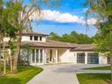 Elegant single-story home showcasing clean white facade, tile roof, three-car garage, and lush landscaping at 5546 Drexel Rd, Land O Lakes, FL 34638