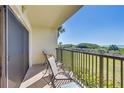 Relaxing balcony view with seating, overlooking tropical foliage and the ocean in the distance at 7564 Bayshore Dr # 207, Treasure Island, FL 33706