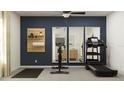 Well-equipped exercise room with a treadmill, stationary bike, and mirrors, set against a stylish dark blue accent wall at 13035 Ruby Gold Ct, Wimauma, FL 33598