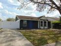 This single-story home features a dark facade and a well-manicured lawn, complemented by a secure white fence at 16147 Sagebrush Rd, Tampa, FL 33618