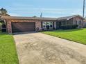 A cozy brick house with a well-maintained front lawn and a driveway leading to an attached garage at 2484 Roberta St, Largo, FL 33771