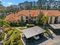 An aerial view of the condo building, parking, and lush landscaping with a red tile roof at 2632 Enterprise E Rd # A23, Clearwater, FL 33759