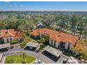 Stunning aerial view of condo buildings featuring tile roofs, carports and lush landscaping under a sunny, blue sky at 2632 Enterprise E Rd # A23, Clearwater, FL 33759