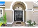 Inviting front entrance featuring an arched entryway with a black door and decorative plants at 26944 Affirmed Dr, Wesley Chapel, FL 33544