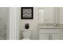 Well-lit powder room featuring a granite countertop, framed artwork, and modern fixtures at 32027 Spiceberry St, San Antonio, FL 33576