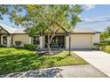Exterior view of a charming single-story home featuring mature trees and a cozy, screened front porch at 3462 Sutton Pl, Palm Harbor, FL 34684
