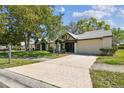 Charming single-story home with well-manicured lawn, large trees and a lengthy driveway leading to an attached garage at 3462 Sutton Pl, Palm Harbor, FL 34684