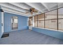 A sun room with blue walls, a ceiling fan, carpet, and large windows with shades at 358 51St N Ave, St Petersburg, FL 33703