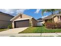 Side view of the property showcasing a well-manicured lawn and a two-car garage at 13052 Ogden Glade Rd, Dade City, FL 33525