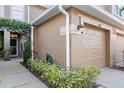 Townhome exterior featuring a one-car garage with neat landscaping and an elegant outdoor light fixture at 18903 Duquesne Dr, Tampa, FL 33647