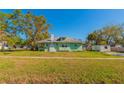 View of the backyard of a green home with a large open lawn at 313 Jefferson S Ave, Oldsmar, FL 34677