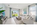 Bright living room featuring tile floors, neutral furniture, and a sliding glass door to the backyard at 31570 Ancient Sage Rd, Wesley Chapel, FL 33545