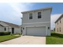 Two-story home with a gray exterior, two-car garage, landscaped front yard, and concrete driveway at 34110 Jasper Stone Dr, Wesley Chapel, FL 33543
