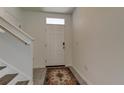 Bright foyer with a white front door, staircase, tiled floor, and an area rug at 34110 Jasper Stone Dr, Wesley Chapel, FL 33543