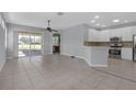 Open-concept living room with tile flooring, sliding glass doors to the lanai, and a seamless connection to the kitchen at 1205 Huntington Greens Dr, Sun City Center, FL 33573