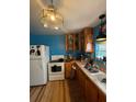 Galley kitchen has wood cabinets, white appliances, bright lighting, and light hardwood floors at 17233 Dalberg Dr, Spring Hill, FL 34610