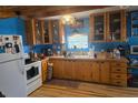 Farmhouse kitchen featuring wood cabinets, blue walls, hardwood floors and a white refrigerator at 17233 Dalberg Dr, Spring Hill, FL 34610