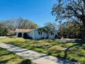 Single-story home with a lush green lawn and mature trees, offering a serene and inviting curb appeal at 2343 Wilshire Dr, Dunedin, FL 34698
